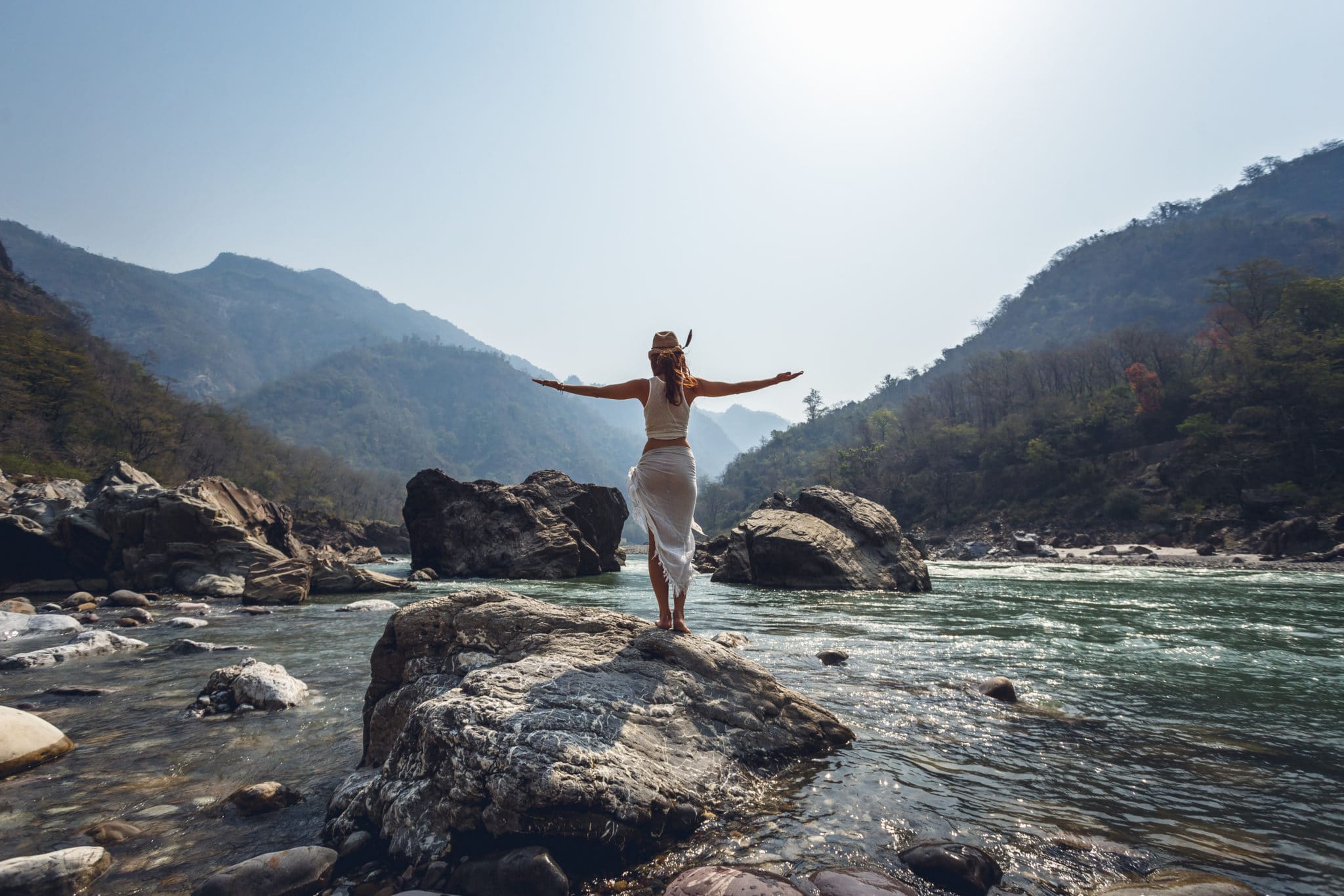 a happy employee standing on a rock in a river