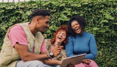 A-group-of-three-laugh-together-and-look-at-a-tablet-screen